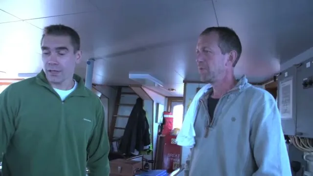 Two crew members beside the ship's controls in the Arctic Sunrise cabin.